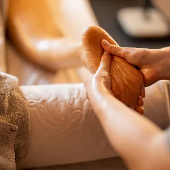 Massage des pieds dans un spa, mains tenant un pied.